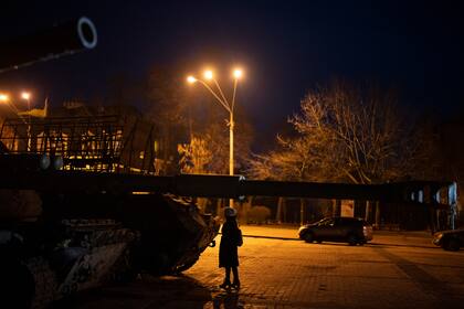 Una mujer parada frente a vehículos blindados y tanques rusos destruidos en el centro de Kiev