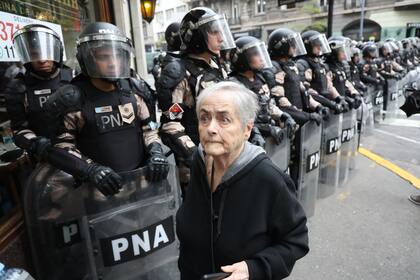 Una mujer pasa al lado de la columna de policías que controlaban el paso en la zona de Congreso