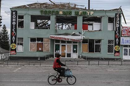 Una mujer pasa con su bici frente a un edificio destruido en la ciudad de Balakliya, en la región de Kharkiv, recapturada por los ucranianos