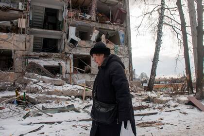 Una mujer pasa frente a un edificio dañado por los bombardeos rusos, el domingo 13 de marzo de 2022, en Járkiv, Ucrania. (AP Foto/Andrew Marienko)