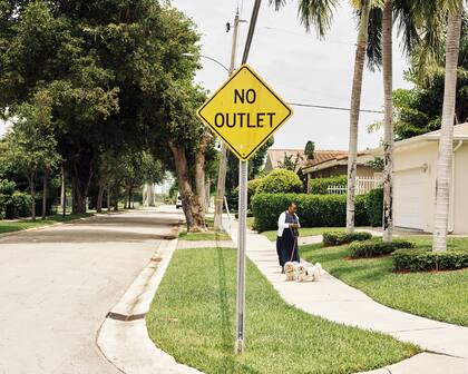 Una mujer pasea a sus perros en el vecindario Little River de Miami; la mayor parte del muro propuesto existiría tierra adentro, paralela a la costa a través de vecindarios como Little River y Shorecrest