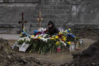 Una mujer permanece junto a las tumbas de dos soldados ucranianos, muertos en batalla, en el cementerio Lychakiv, en Lviv.