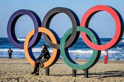 Una mujer posa en los anillos olímpicos en la playa de Gyeongpo en Gangneung
