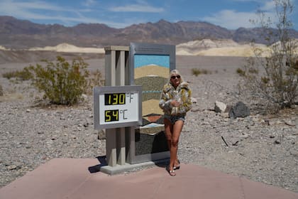 Una mujer posa junto a un termómetro el domingo 16 de julio de 2023, en el Parque Nacional del Valle de la Muerte, California. (AP Foto/John Locher)