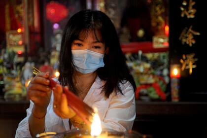 Una mujer quema varitas de incienso para rezar en un templo chino el primer día del Año Nuevo Lunar en Kuta, en la localidad de Bali, Indonesia