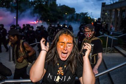 Una mujer reacciona después de ser rociada con gas pimienta al lado del Capitolio del Estado de Colorado mientras las protestas contra la muerte de George Floyd continúan por tercera noche el 30 de mayo de 2020 en Denver, Colorado