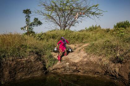 Una mujer recoge agua de un pozo que estaba casi seco, pero se llenó por el monzón.