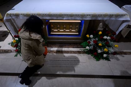 Una mujer reza junto a la urna con los restos de la Madre Francisca Rubatto en una capilla en Montevideo, mientras el Papa Francisco la canoniza en el Vaticano 