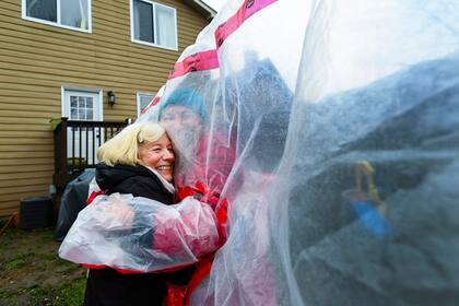 Una mujer se abraza con su madre a través de un plástico protector en los festejos navideños en Ontario, Canada