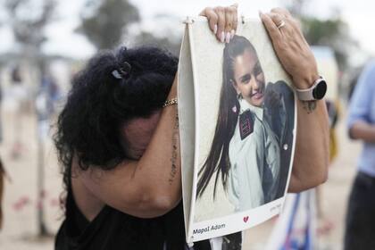Una mujer se apoya en una fotografía de Mapal Adam, en el lugar donde se celebró el festival de música Nova, donde cientos de personas fueron asesinadas y secuestradas por Hamas y llevadas a Gaza, en el primer aniversario del ataque, cerca del kibutz Reim, en el sur de Israel, el lunes 7 de octubre de 2024
