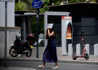 Una mujer se cubre la cabeza mientras camina durante una ola de calor en Sevilla el 10 de julio de 2023