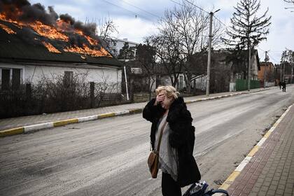 Una mujer se lamenta frente a una casa en llamas luego de un bombardeo en la ciudad de Irpin, en las afueras de Kiev, el 4 de marzo de 2022.