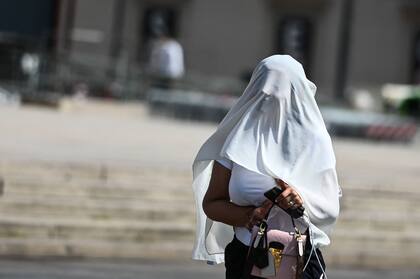 Una mujer se protege del sol con un pareo blanco en Milán, en medio de la ola de calor que afecta a toda Italia