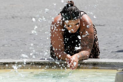 Una mujer se refresca de las altas temperaturas en una fuente en Roma, el 18 de julio de 2023. (AP Foto/Gregorio Borgia)