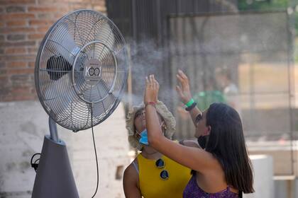Una mujer se refresca en un ventilador nebulizando agua junto al Coliseo, en Roma