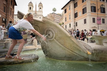 Una mujer se refresca en una fuente de la Piazza di Spagna en Roma, donde se espera que las temperaturas suban hasta los 39 grados el 20 de junio de 2024.