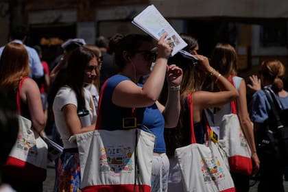 Una mujer se resguarda del sol con una guía turística en el centro de Roma, mientras se espera que las temperaturas alcancen los 32 grados, el martes 26 de mayo de 2026 (AP/Gregorio Borgia)