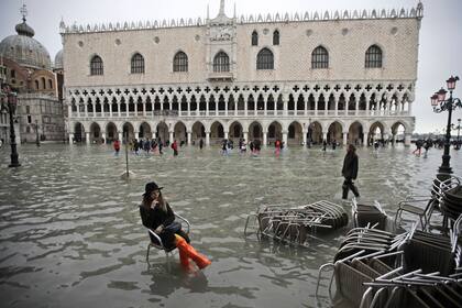 Una mujer se sienta en una silla en una plaza inundada de San Marcos, en Venecia, el 13 de noviembre de 2019