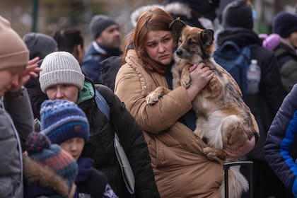 Una mujer sostiene a su perro después de llegar a la frontera entre Ucrania y Polonia en Korczowa