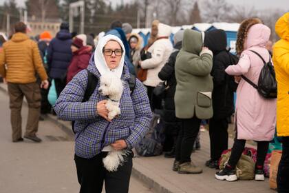 Una mujer sostiene a su perro en el cruce fronterizo en Medyka, Polonia