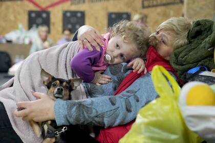 Una mujer sostiene a un niño y a un perro en un refugio dentro de un edificio en Mariupol, Ucrania