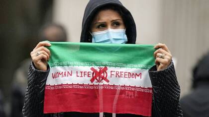 Una mujer sostiene cartel de protesta con el lema "Mujer, vida y libertad"