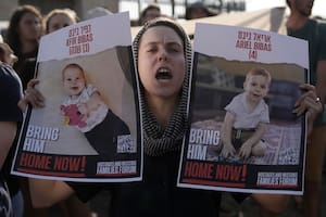 Una mujer sostiene carteles de Kfir y Ariel Bibas, cautivos de Hamás junto con sus padres en la Gaza, durante una marcha hacia la Knesset, el Parlamento de Israel, para pedir un acuerdo para liberar a los rehenes, en Jerusalén, el jueves 13 de junio de 2024.