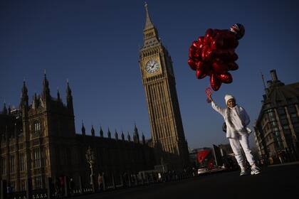 Una mujer sostiene globos en el puente de Westminster, de fondo el "Big Ben", Londres