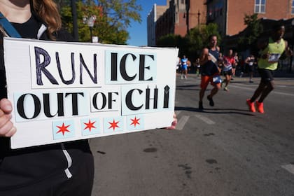 Una mujer sostiene un cartel en el que pide la salida de los agentes del Servicio de Inmigración y Control de Aduanas de la ciudad, el 12 de octubre de 2025, durante el Maratón de Chicago.