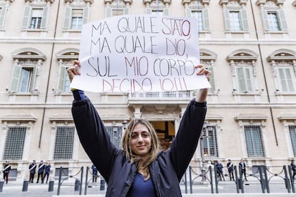 Una mujer sostiene un cartel en italiano que dice "¿Qué Estado, qué Dios? Sólo yo decido sobre mi cuerpo", frente al Senado italiano en Roma, el 22 de abril de 2024. (Roberto Monaldo /LaPresse via AP)