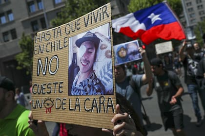 Una mujer sostiene un cartel que dice: "Hasta que vivir en Chile no cueste un ojo de la cara", durante una protesta en apoyo de los manifestantes que resultaron heridos en el ojo por la policía chilena