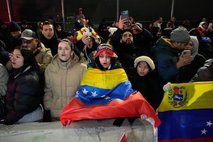 Una mujer sostiene una bandera venezolana mientras opositores del presidente Nicolás Maduro corean frente al Centro de Detención Metropolitano, donde él se encuentra detenido, el sábado 3 de enero de 2026, en Nueva York