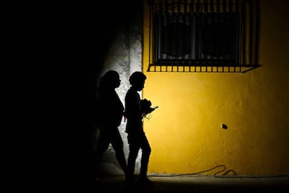 Una mujer sostiene una linterna mientras camina con un hombre por una calle durante un apagón en La Habana el 16 de marzo de 2026. Cuba sufrió un corte de energía generalizado el 16 de marzo de 2026, según la compañía eléctrica nacional, en el contexto de una grave crisis en la isla provocada por el bloqueo energético estadounidense