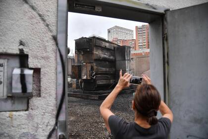 Una mujer toma una foto de la subestación eléctrica dañada en Caracas, donde se produjeron explosiones de causa desconocida a principios del 11 de marzo de 2019, mientras continúa un apagón masivo que afecta a algunas zonas del país.