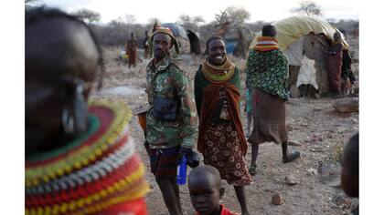Una mujer Turkana sonríe mientras que los hombres vuelven a casa con su ganado