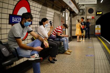 Una mujer usa un ventilador portátil para enfriarse en una plataforma de la estación de metro de Londres el 31 de julio de 2020