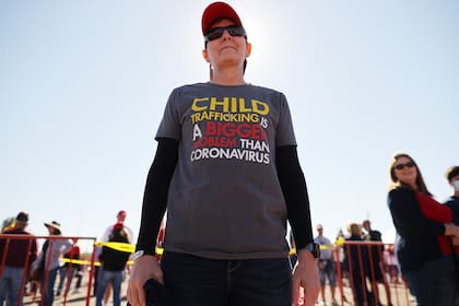 Una mujer usa una camisa que promueve una teoría de la conspiración promovida por el grupo QAnon mientras espera en la fila para asistir a un mitin de campaña con el presidente de los Estados Unidos, Donald Trump, en el aeropuerto Phoenix Goodyear, el 28 de octubre de 2020 en Goodyear, Arizona