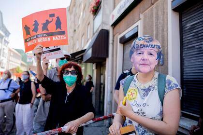 Una mujer usa una máscara de la canciller de Alemania, Angela Merkel, con la inscripción "Adiós democracia", durante una manifestación organizada por el grupo Querdenken 711, en contra de las medidas restrictivas impuestas por el gobierno para frenar el propagación del coronavirus