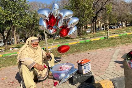 Una mujer vende globos de color rojo brillante en forma de corazón en un puesto improvisado para el Día de San Valentín en Islamabad, Pakistán