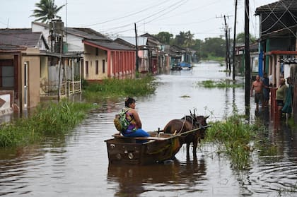 Una mujer viaja en un carruaje tirado por caballos por una calle inundada en Batabano, provincia de Mayabeque, Cuba, durante el paso de la tormenta tropical Idalia.