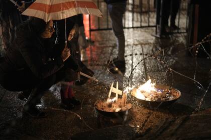 Una mujer y un niño encienden una vela junto a una escena de Navidad decorada en homenaje a las víctimas de Gaza