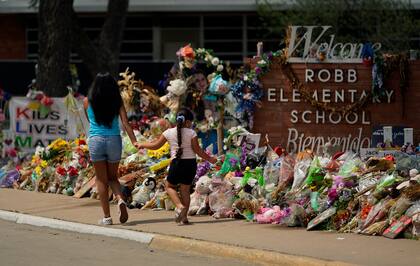 Una mujer y una niña caminan frente a un sitio de homenaje en la escuela primaria Robb, el martes 12 de julio de 2022, en Uvalde, Texas. (AP Foto/Eric Gay)