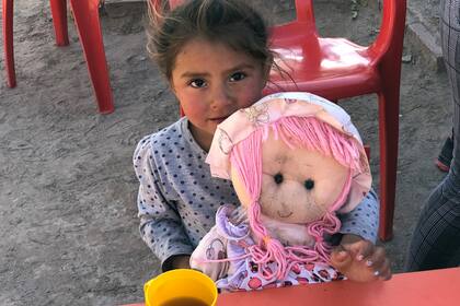 Una nena toma la merienda en el Espacio de Primera Infancia (EPI) de Manga Bajada junto a su muñeca. Consiste en mate cocido, libritos, alfajorcitos de maicena y facturas. El resto del tiempo reciben estimulación y atención médica.