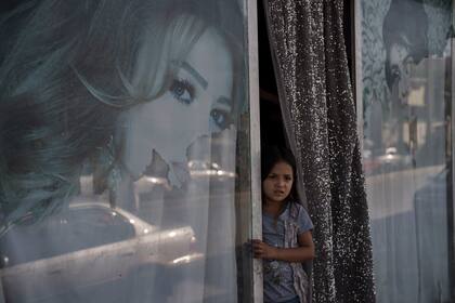 Una niña afgana mira desde un salón de belleza en Kabul, Afganistán, el jueves 16 de septiembre de 2021