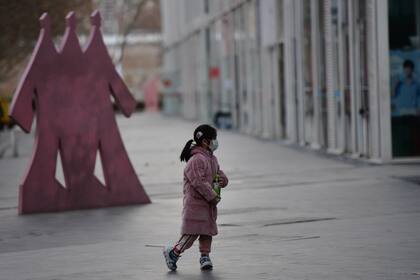 Una niña camina con un barbijo por las calles desoladas de Pekín