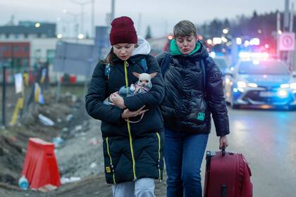 Una niña de Ucrania sostiene a un perro mientras llega con otra mujer al cruce fronterizo en Medyka, al sureste de Polonia