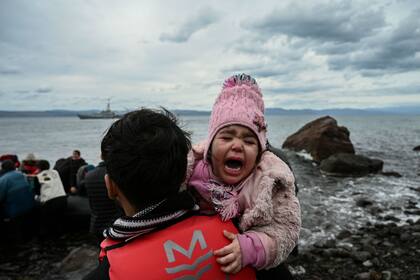 Una niña llora al llegar en bote con otros 54 refugiados afganos a la isla griega de Lesbos el 28 de febrero de 2020
