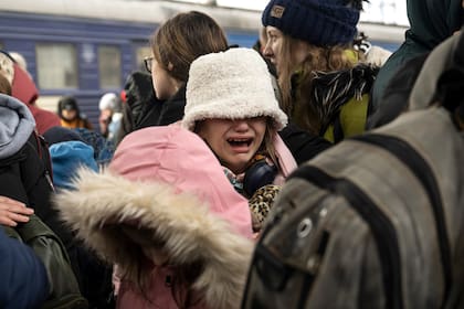 Una niña llora mientras se aproximan al tren que se dirige al oeste hacia Lviv, en la estación principal de trenes en Kiev, hoy 4 de marzo de 2022