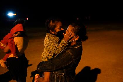 Una niña migrante de Honduras besa a su madre a través de los barbijos en un área de admisión luego de cruzar la frontera en La Joya, estado de Texas