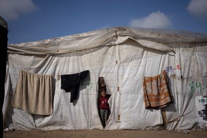Una niña palestina se asoma a una de las tiendas de un asentamiento improvisado en Rafah, el 23 de enero de 2024. (AP/Fatima Shbair)